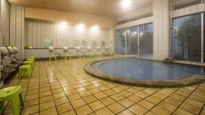 Un área de piscina con suelo de baldosas, taburetes verdes y un amplio ventanal.