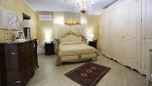Ein Schlafzimmer mit Bett, Kleiderschrank, Schminktisch und einer Chandelier.