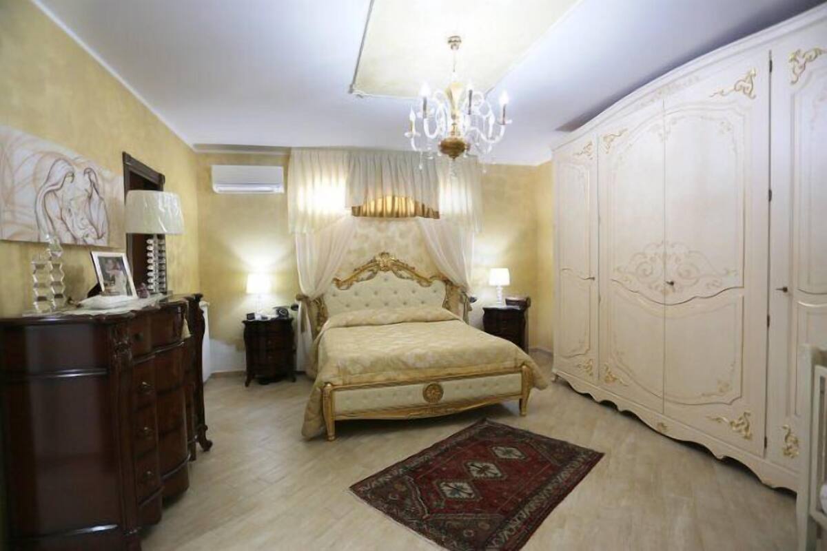 Un dormitorio con cama, armario, cómoda y candelabro.