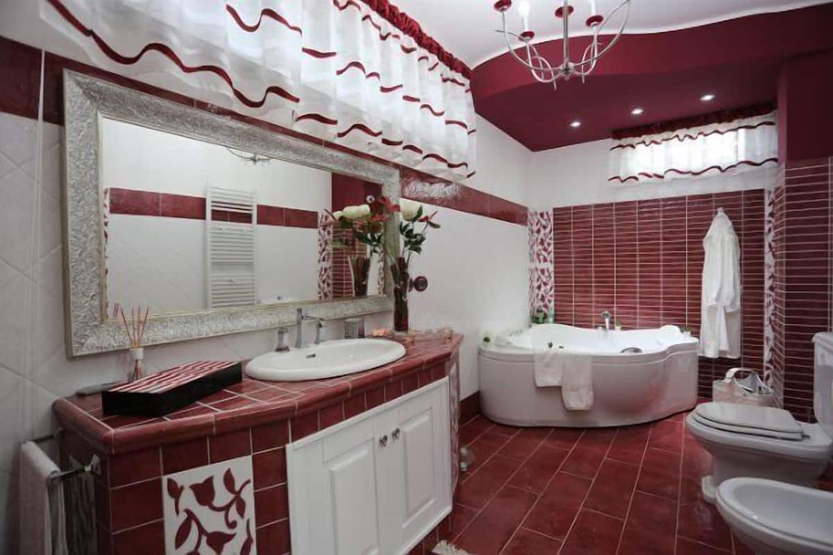 Un baño con un espejo grande, dos lavamanos, una bañera y un inodoro.