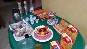 Ein reichhaltiges Buffet mit verschiedenen Speisen, darunter Gebäck, Früchte und Saftkartons.