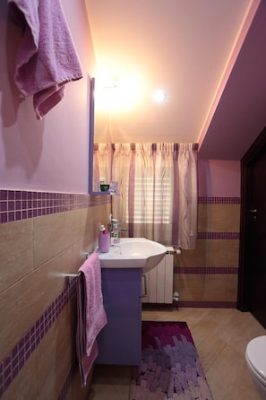 Une salle de bain avec un lavabo, un miroir et un rideau de douche.