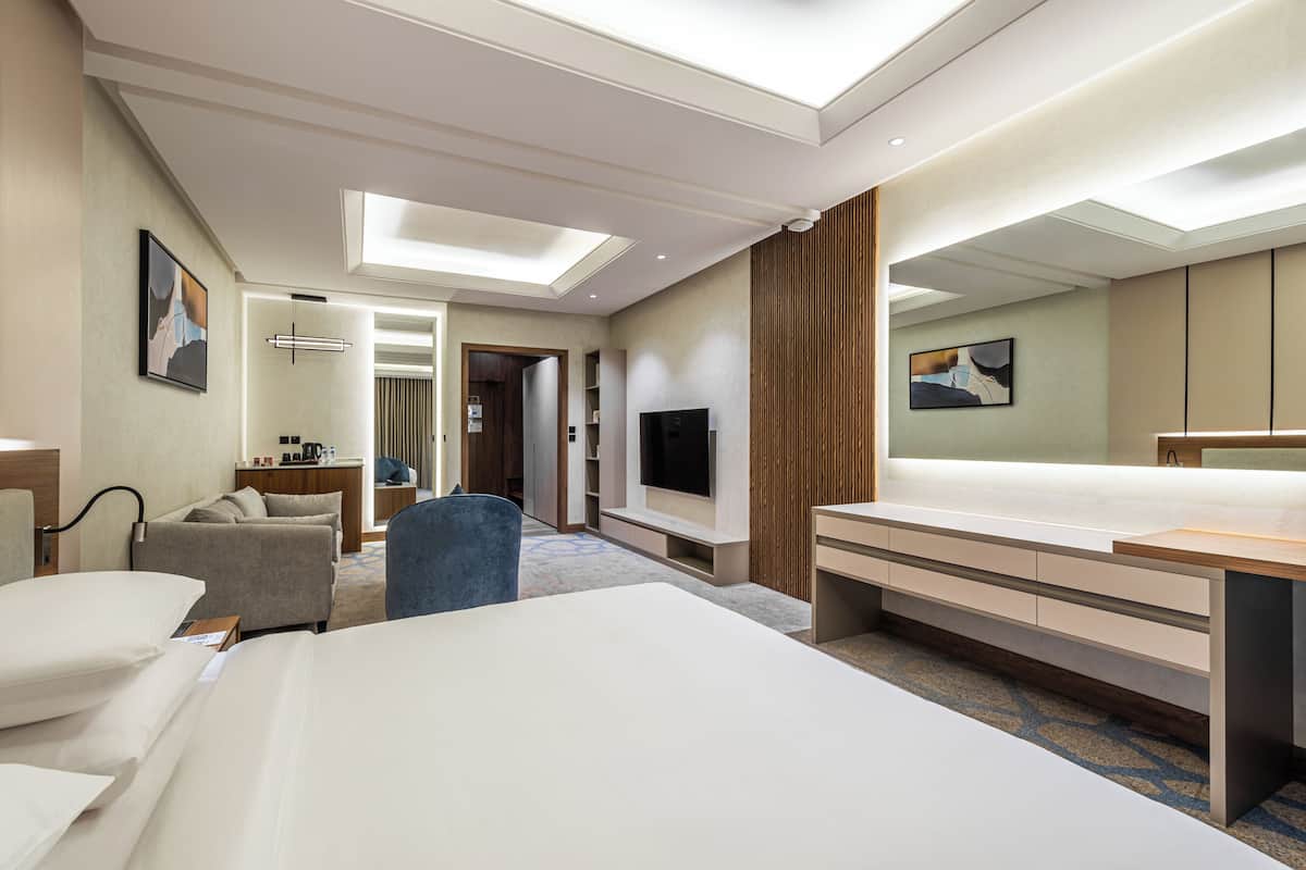 Una habitación de hotel con una cama grande, un escritorio, un televisor y una zona de estar.
