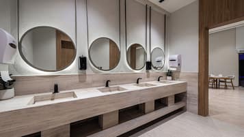 A modern bathroom with multiple sinks, round mirrors, and a wooden panel design.