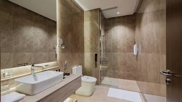 Un baño moderno con un lavamanos grande, inodoro y cabina de ducha con mampara de vidrio.