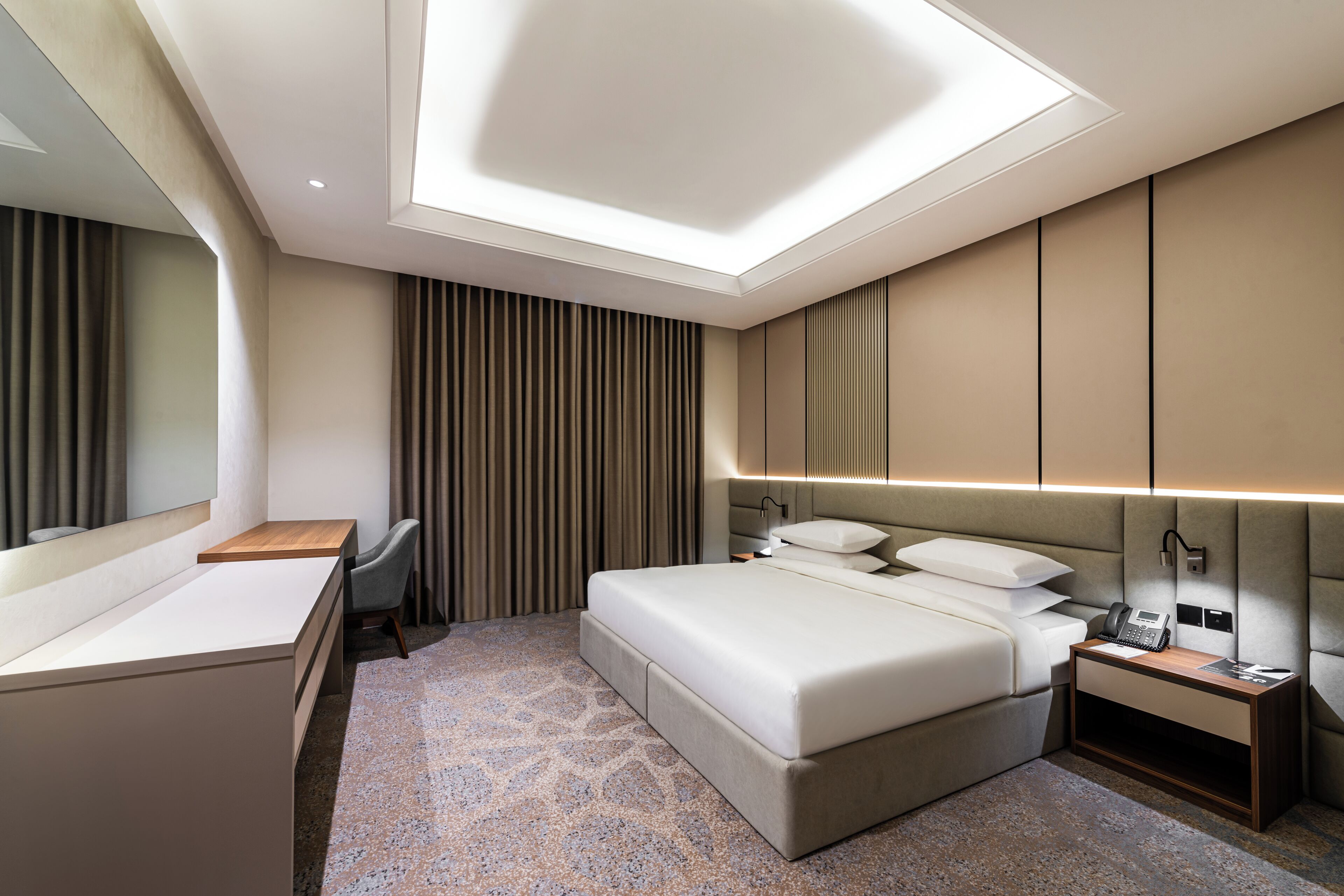 Ein modernes Hotelzimmer mit einem großen Bett, einem Schreibtisch und einem Schminktisch.