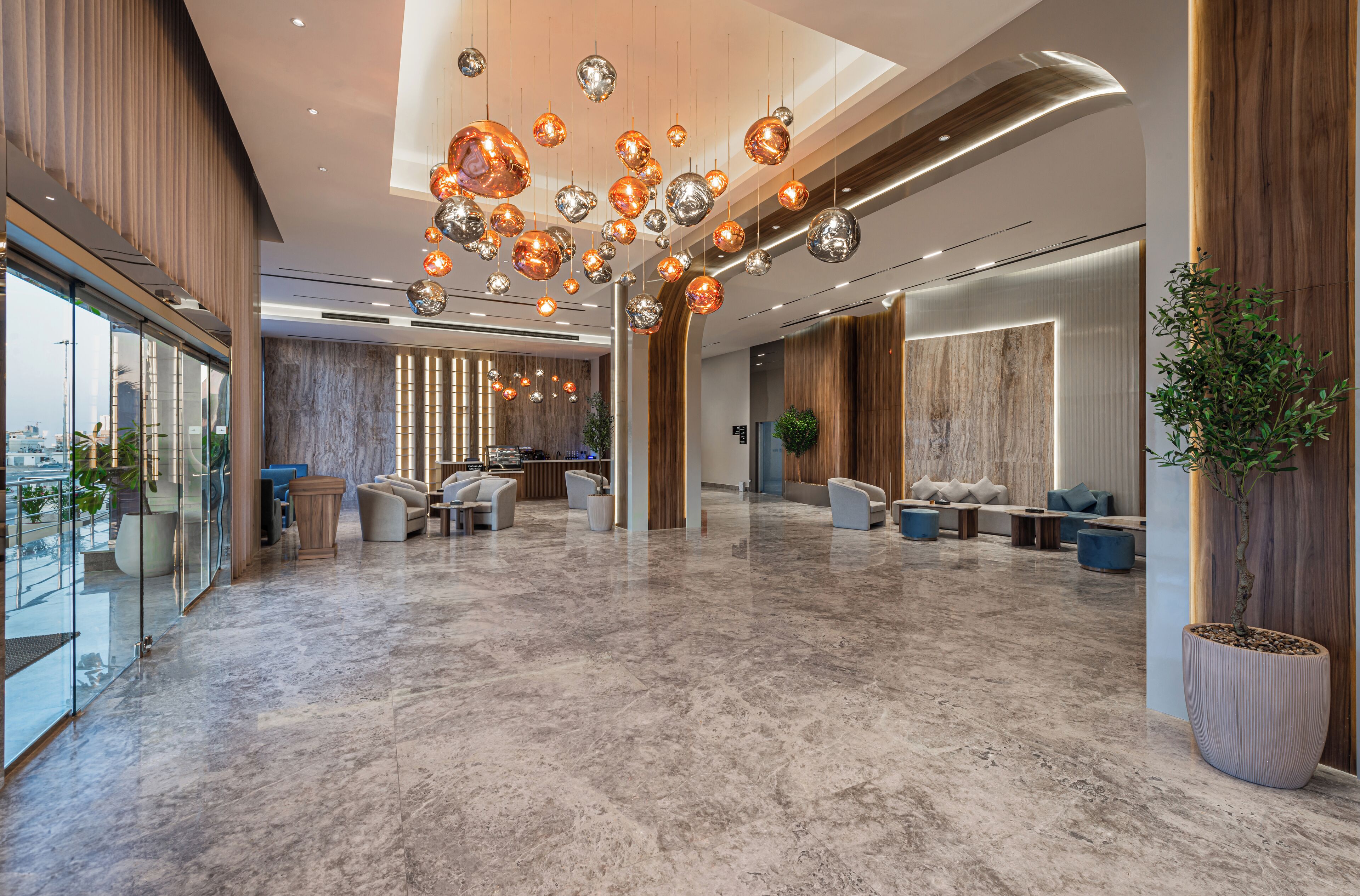 A spacious lobby with a marble floor, modern seating, and a large reception desk.