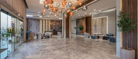 A spacious lobby with a marble floor, modern seating, and a large reception desk.