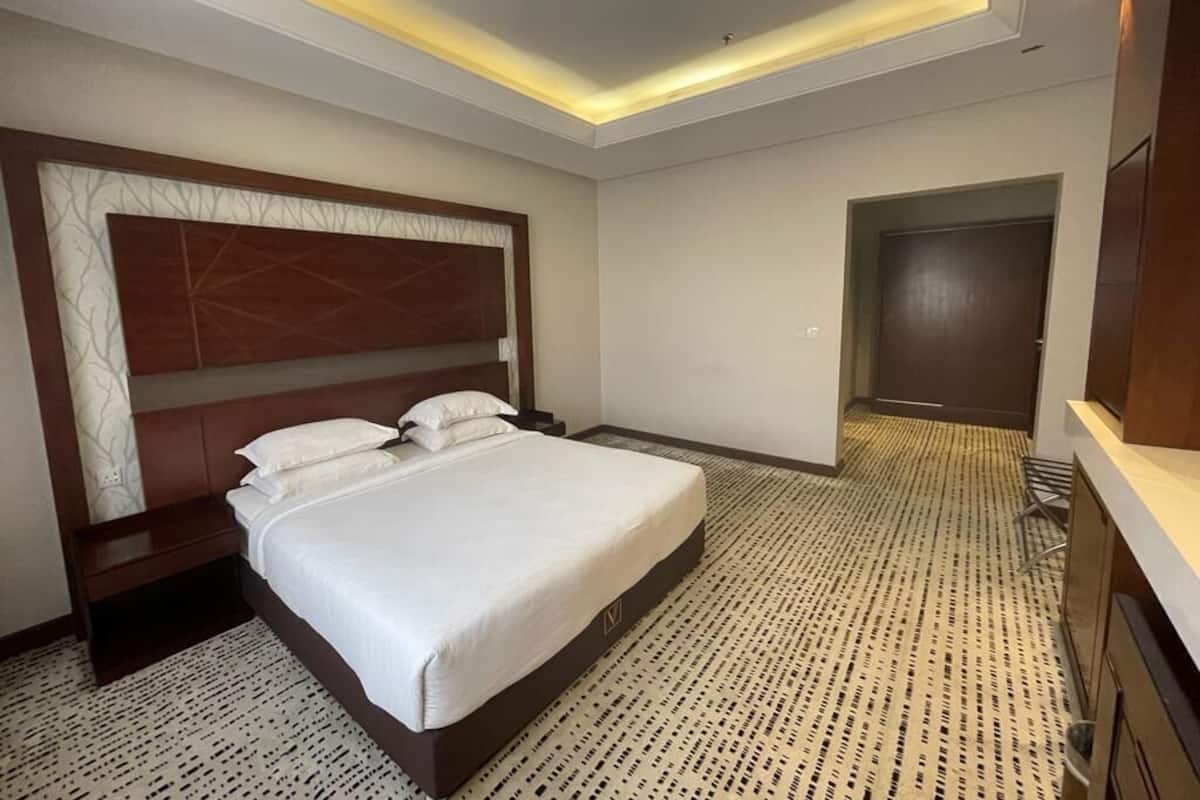 Una habitación de hotel con una cama grande, un cabecero de madera, una mesita de noche y un armario.