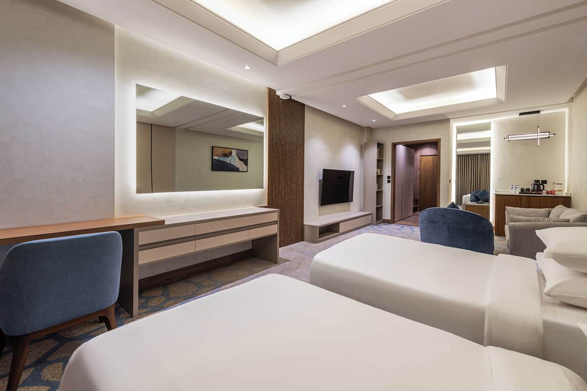 Una habitación de hotel con una cama grande, un escritorio con una silla, un televisor y un espejo.