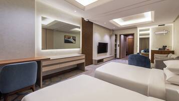 A hotel room with a large bed, a desk with a chair, a TV, and a mirror.