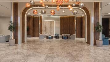 A spacious lobby with a marble floor, modern seating, and decorative hanging lights.