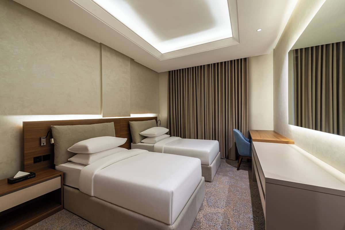 Habitación de hotel con dos camas, un escritorio y una silla.