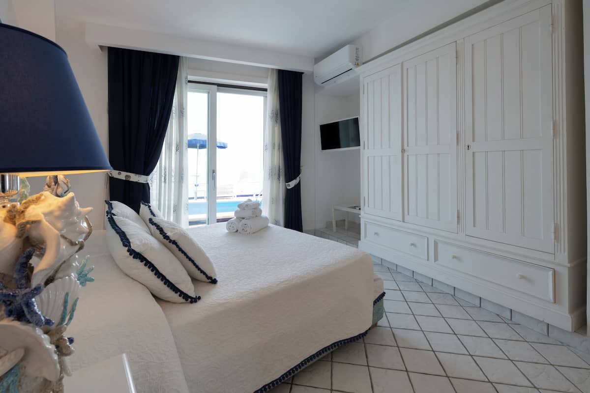 A hotel room with a bed, a TV mounted on the wall, and a large wardrobe.