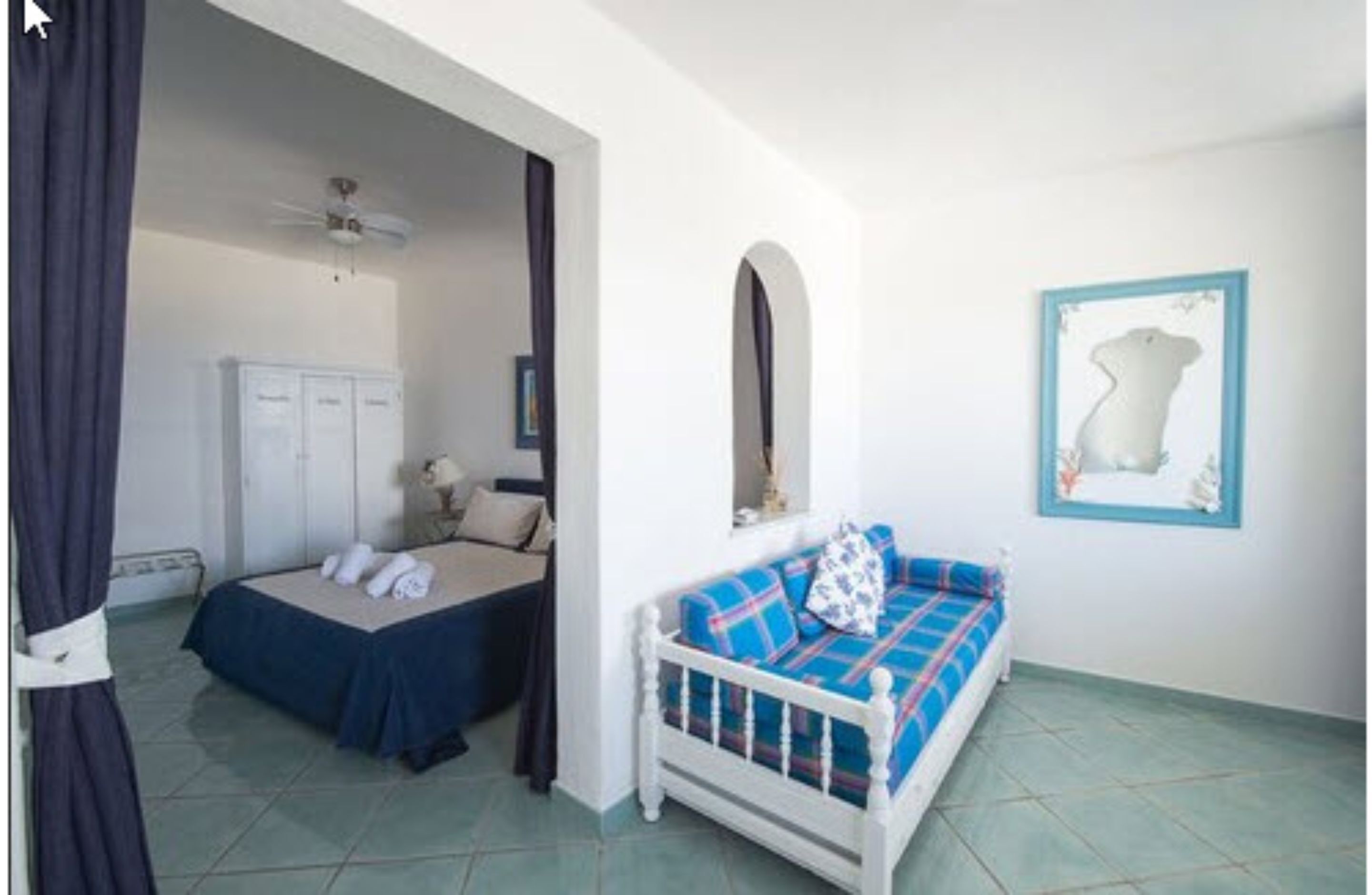 Um quarto com uma cama, um sofá, um guarda-roupa e um ventilador de teto.