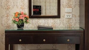 Een houten bureau met een spiegel, een vaas met bloemen en een bank.