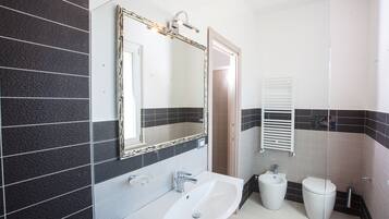 Ein Badezimmer mit Waschbecken, Spiegel, Bidet und Toilette.