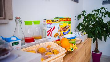 Un bufé de desayuno con cajas de cereales, jugo y frutas.