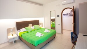 A modern bedroom with a large bed, green bedding, a nightstand with a lamp, and a chair. - Il Gallo con gli Stivali (Termoli)