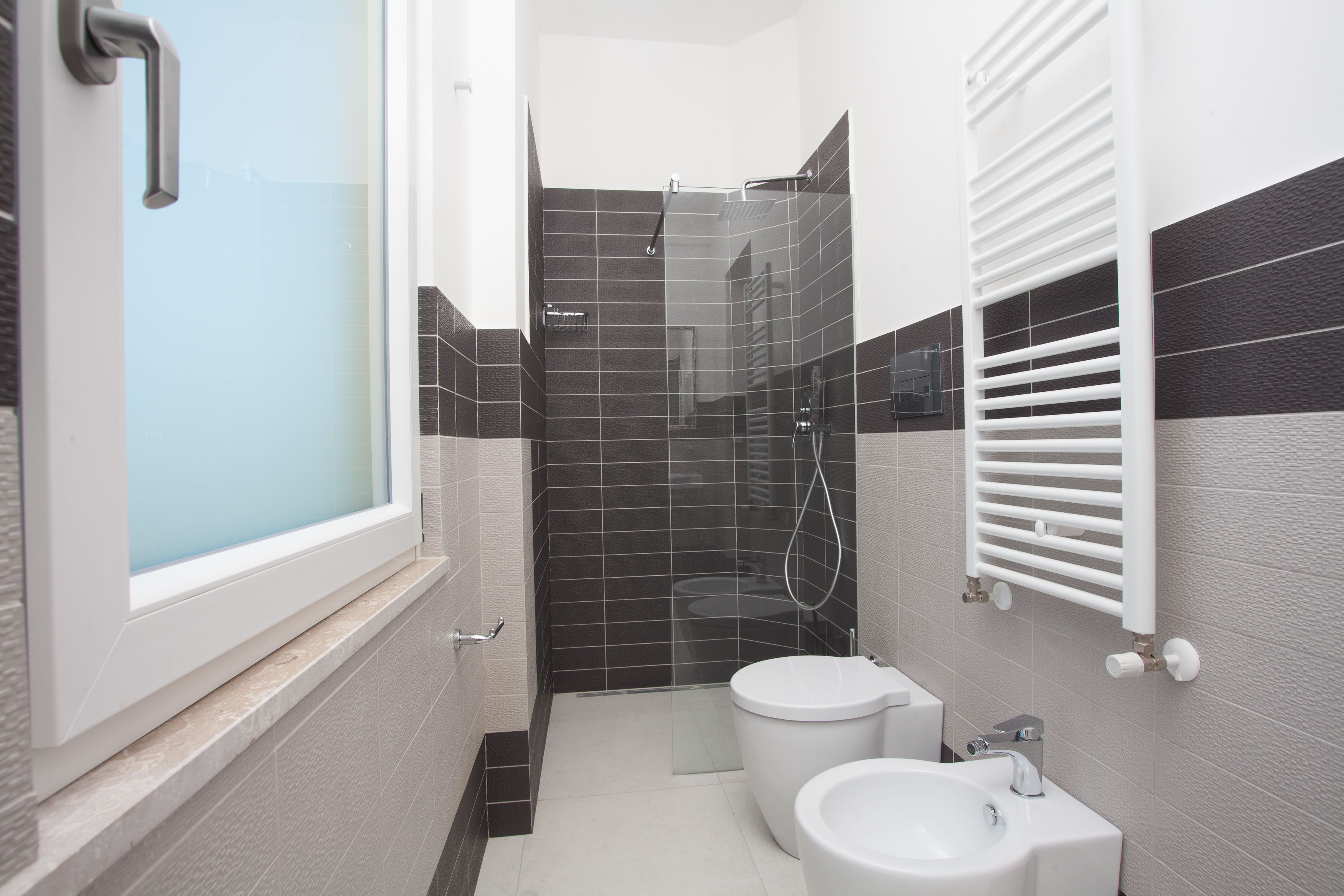 A modern bathroom with a glass shower enclosure, a toilet, and a bidet.