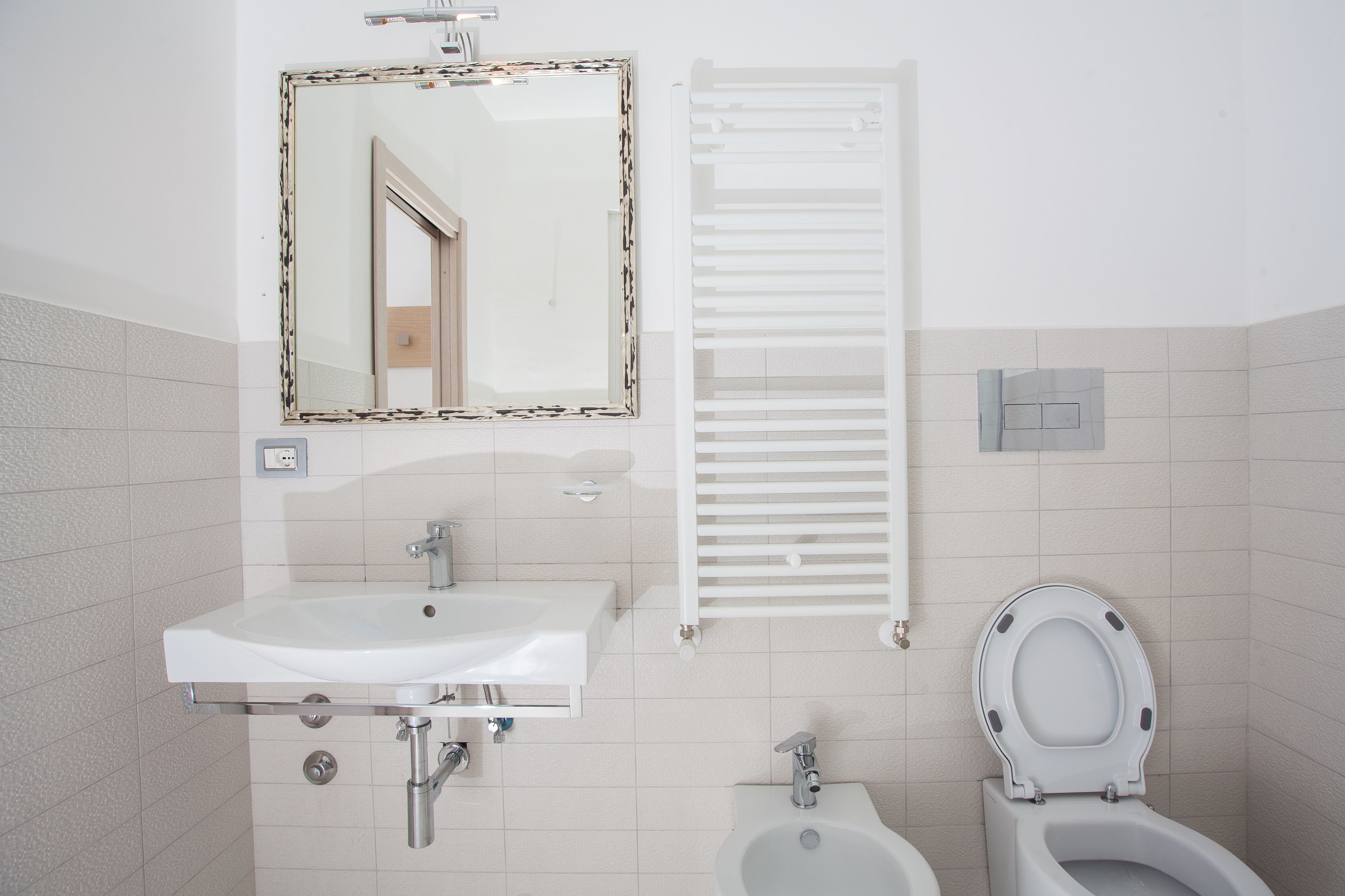 A bathroom with a white sink, mirror, toilet, and bidet.