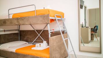 Una cama litera con una manta naranja, una escalera y una mesita con una botella y una taza.