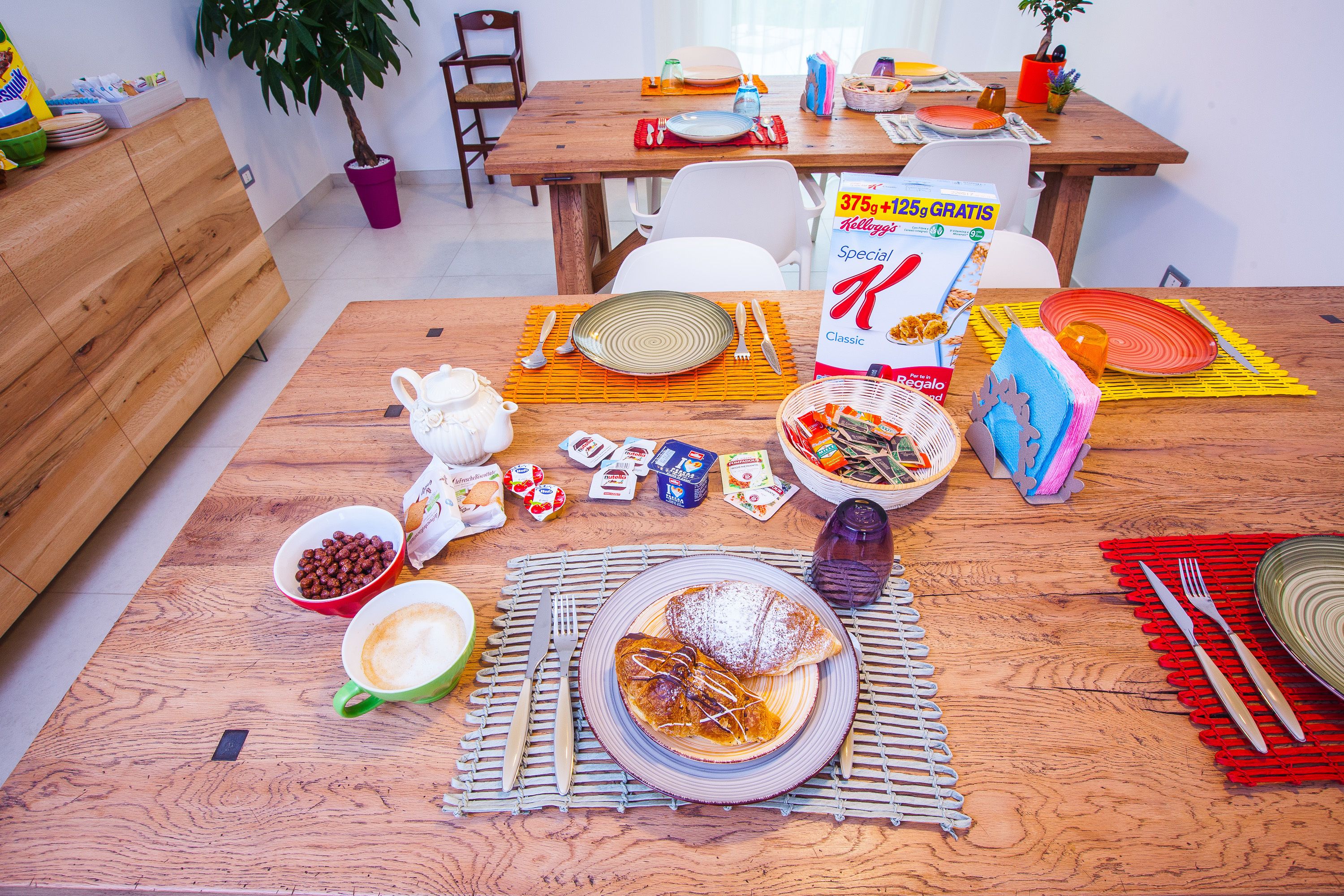 A dining table set with plates, cutlery, and various food items, indicating a meal setting.