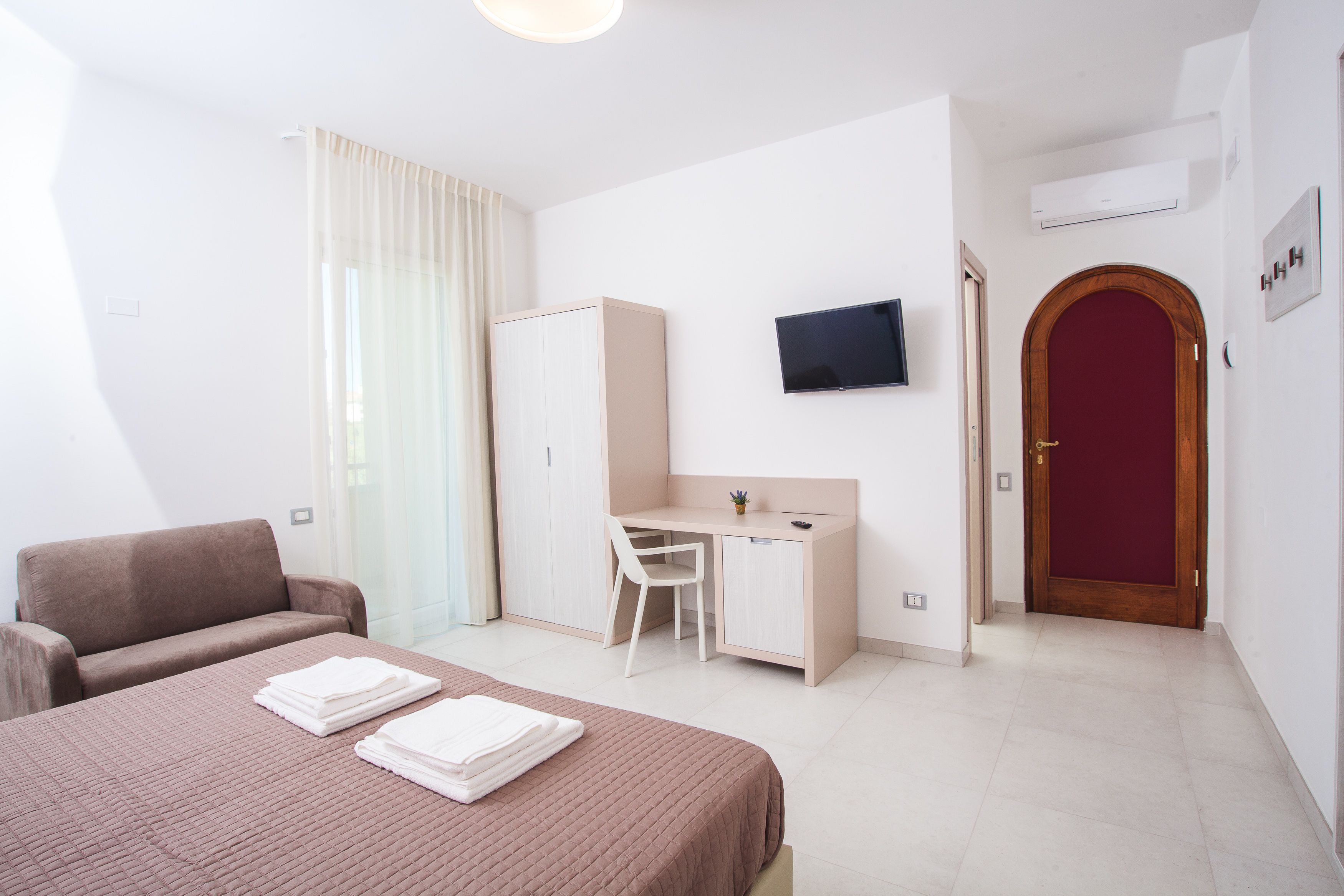 Un dormitorio con cama, escritorio, silla, televisor y armario.