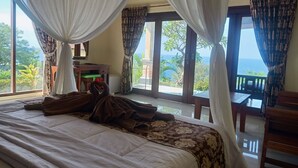 Una camera da letto con un letto grande, una scrivania e vista sull'oceano.