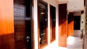 Un pasillo con puertas de madera y suelo de baldosas.