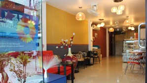A hotel lobby with a reception desk, seating area, and a staircase leading to the upper floor. - Tulip Inn (Patong)