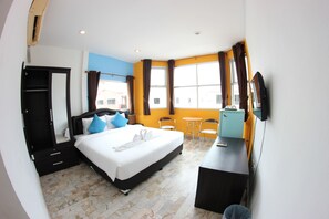 A hotel room with a bed, a desk, a chair, a TV, and a window with curtains. - Tulip Inn (Patong)