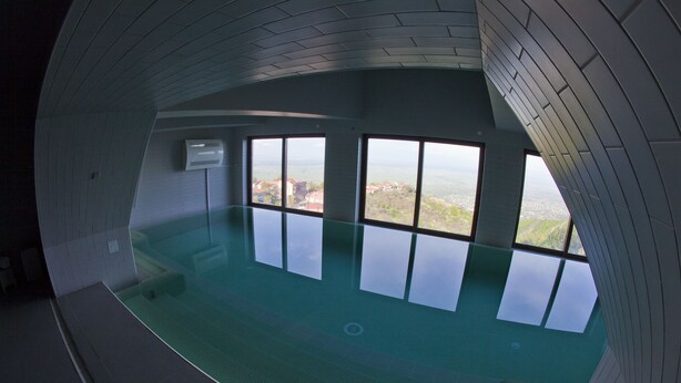 Ein großes Hallenbad mit Blick auf eine entfernte Landschaft durch große Fenster.