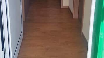 Un pasillo con piso de madera que conduce a una habitación con cama y ventana.