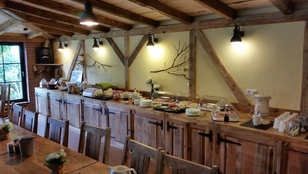 Un comedor rústico con muebles de madera, una mesa larga y una barra con diversos alimentos y condimentos.