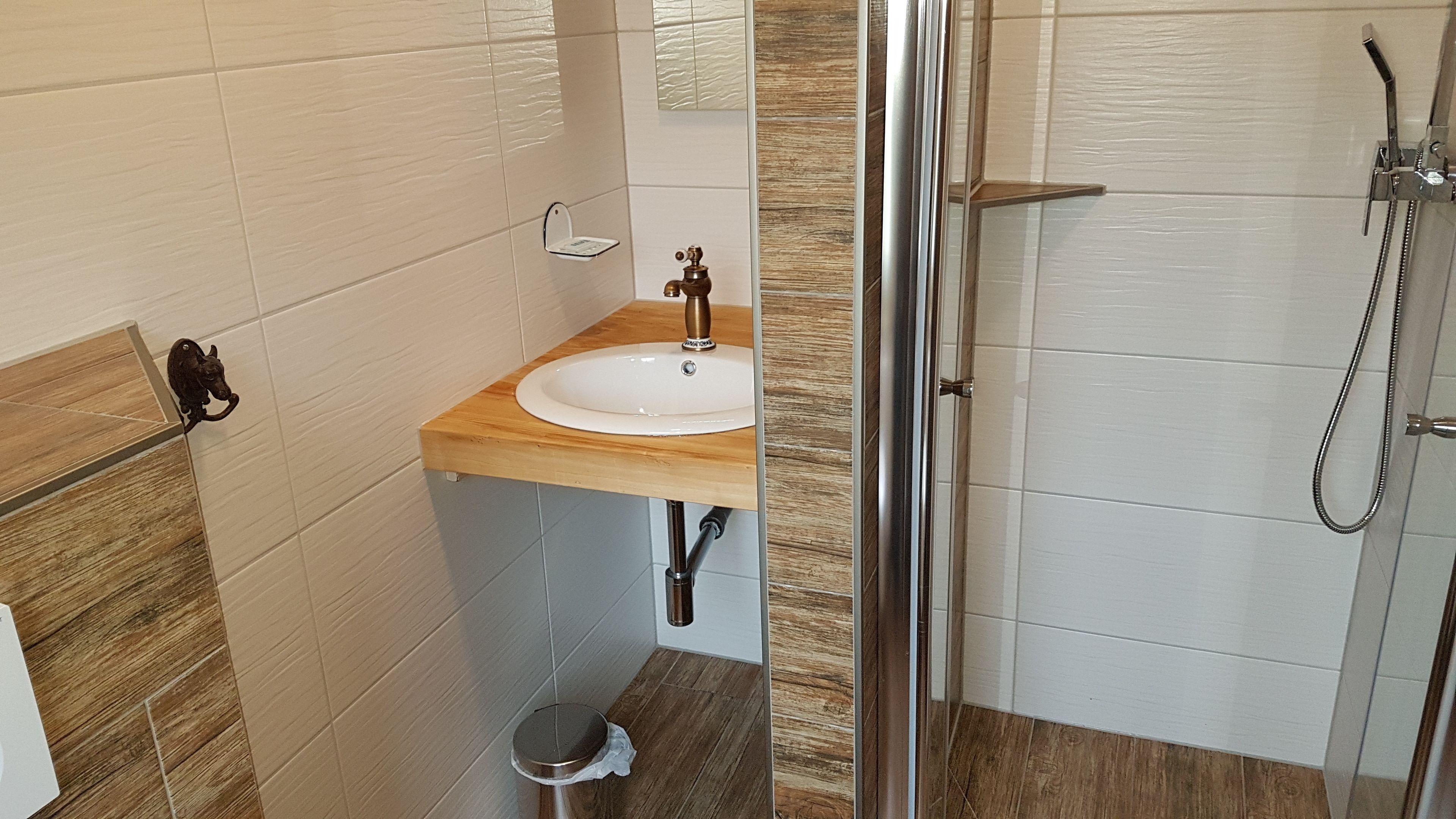 Un baño con tocador de madera, un lavabo blanco y cabina de ducha de vidrio.
