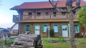 Una casa de madera de dos pisos con balcón y ventanas con marco verde.