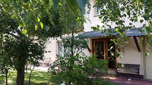 Une maison dotée d’un porche abrité, d’une pelouse et d’un jardin.