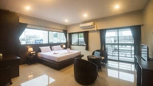 A modern hotel room with a large bed, a desk, a chair, and a TV.