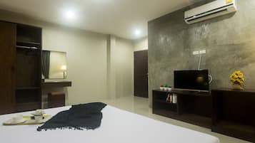Quarto de hotel moderno com cama, televisão, guarda-roupa, espelho e unidade de ar condicionado.