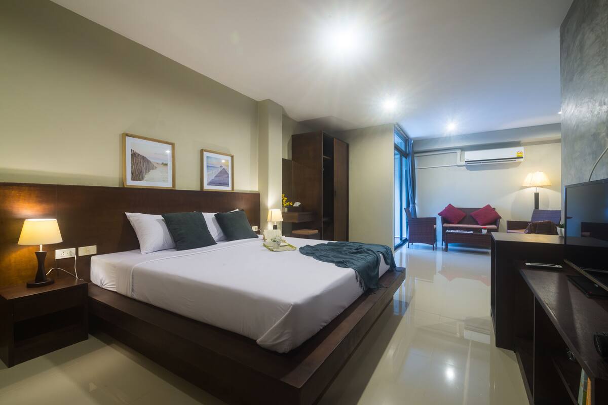A hotel room with a large bed, a desk, a chair, and a TV.