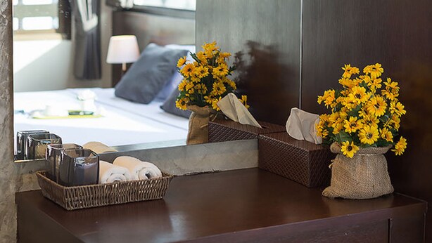 A modern bathroom with a large mirror, a wooden vanity, and a vase of yellow flowers.