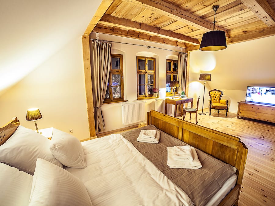 A bedroom with a wooden bed, a desk, a chair, and a television.