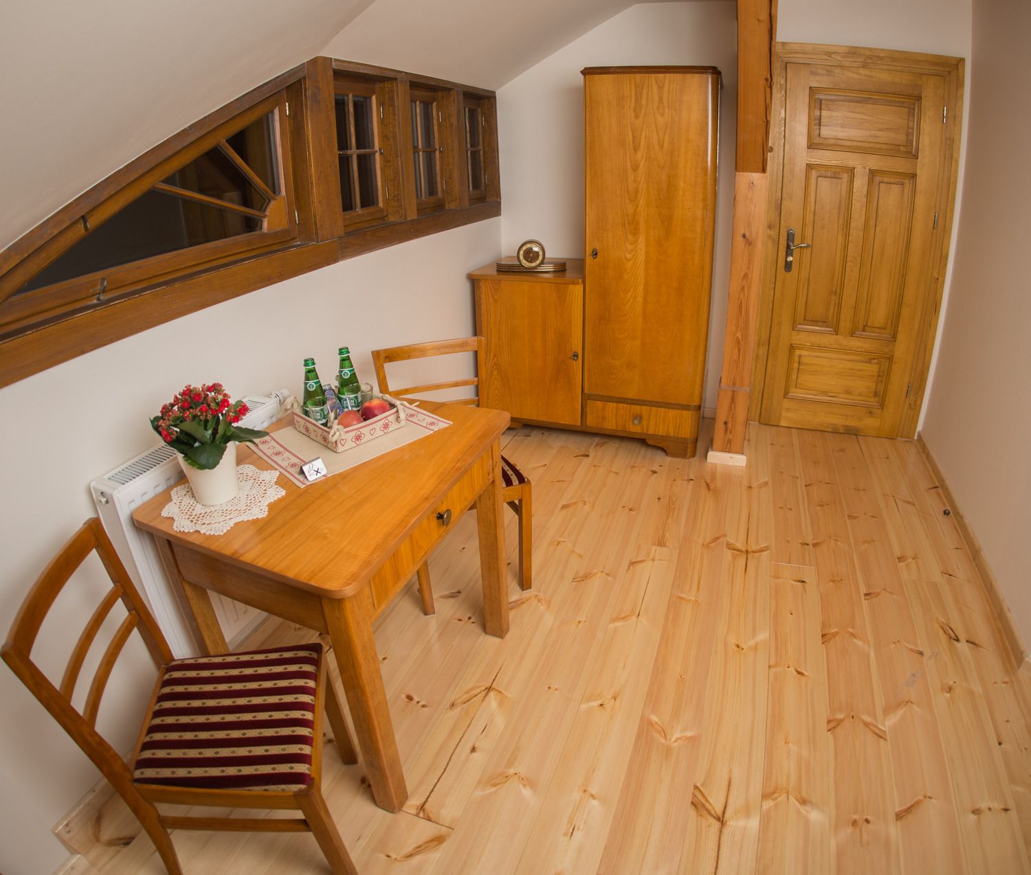 Un pequeño comedor con mesa de madera, sillas y un armario.