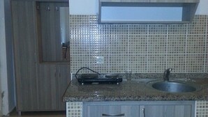 A compact kitchen with a granite countertop, a sink, and wooden cabinets. - Cennet Apart (Bodrum)