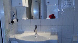 A bathroom with a white sink, a mirror, and a red rose on the wall. - Cennet Apart (Bodrum)