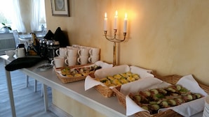Une table de buffet garnie de divers plats, un chandelier avec des bougies et des piles de tasses blanches.