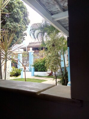 A view of a building with a blue exterior, a thatched roof structure, and surrounding greenery including palm trees and shrubs. - Pousada Armonia (Jijoca de Jericoacoara)
