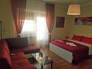 Een hotelkamer met een bed, een bank, een glazen bijzettafeltje en een lamp.