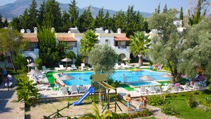 Un resort con piscina, sillones de descanso y un parque infantil.